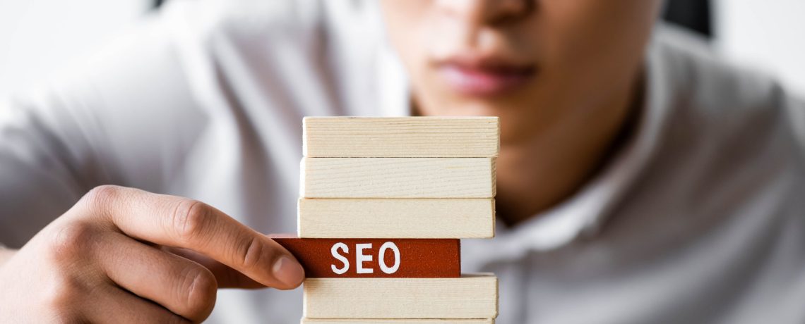 selective focus of asian seo manager holding wooden rectangle with lettering seo