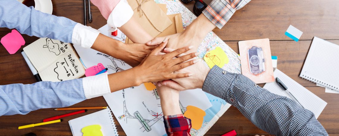 Picture of businessmen's hands on wooden table with documents, coffee and drafts