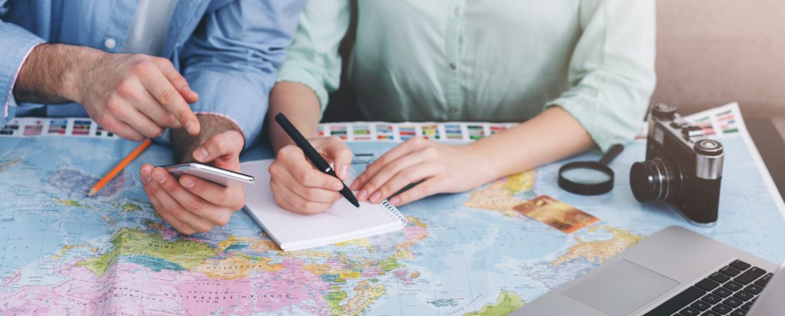 Couple planning vacation trip, writing notes and searching information on laptop