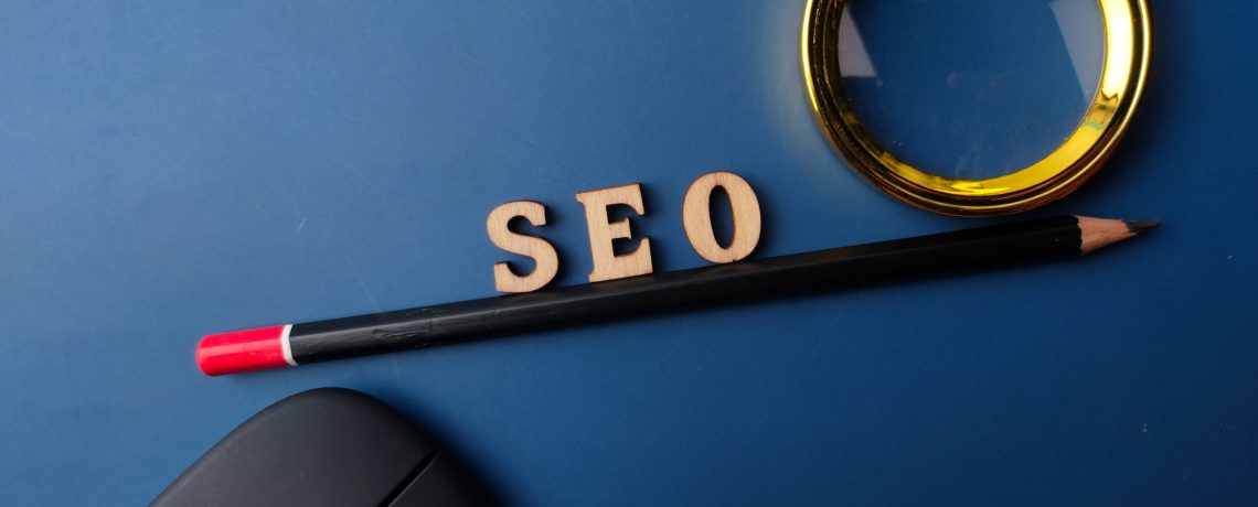Top view pencil and word SEO with black magnifying glass on a blue background
