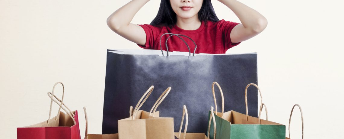 Asian woman shocked with so many shopping bags with white wall background