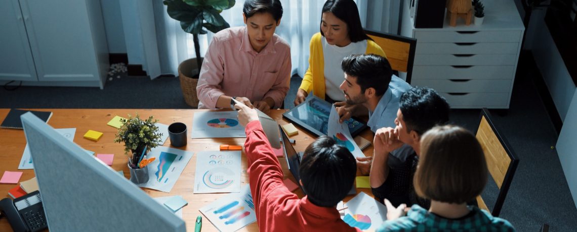 Top view of skilled business team discussing and talking about financial statistic to make decision for investment. Creative project manager looking at data analysis from laptop screen. Convocation.
