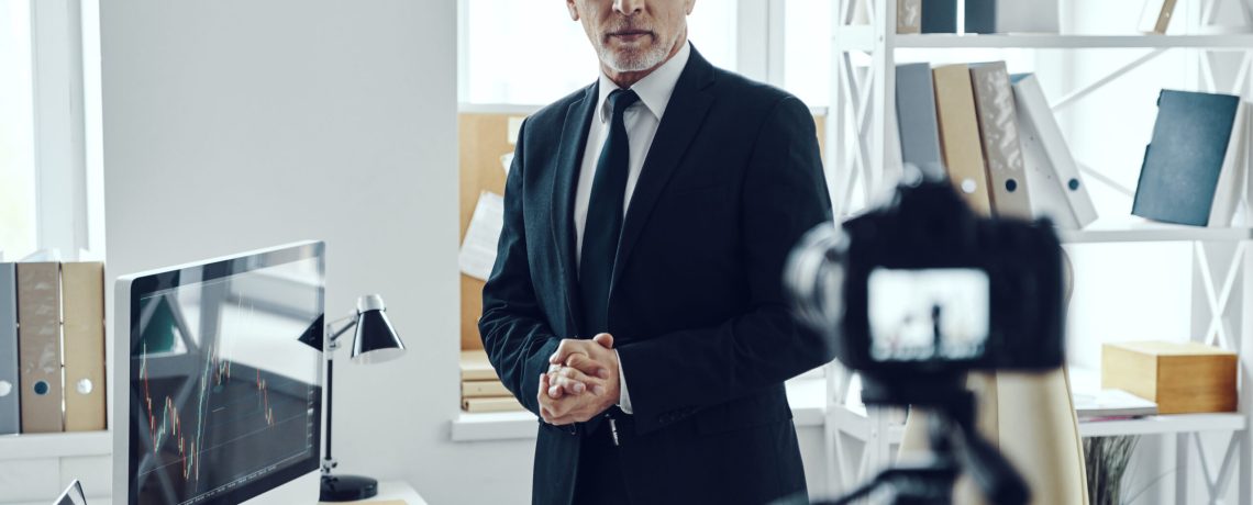 Senior man in elegant business suit sharing his business experience while making social media video