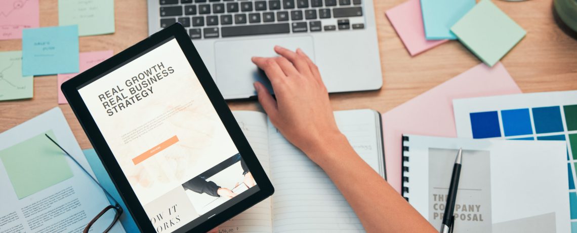 Tablet screen, laptop and hand, business website and paperwork, company proposal and workspace. Person at desk, corporate growth and digital market research strategy, sticky note and ideas top view.